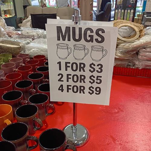 Handwritten mug pricing sign on a display table