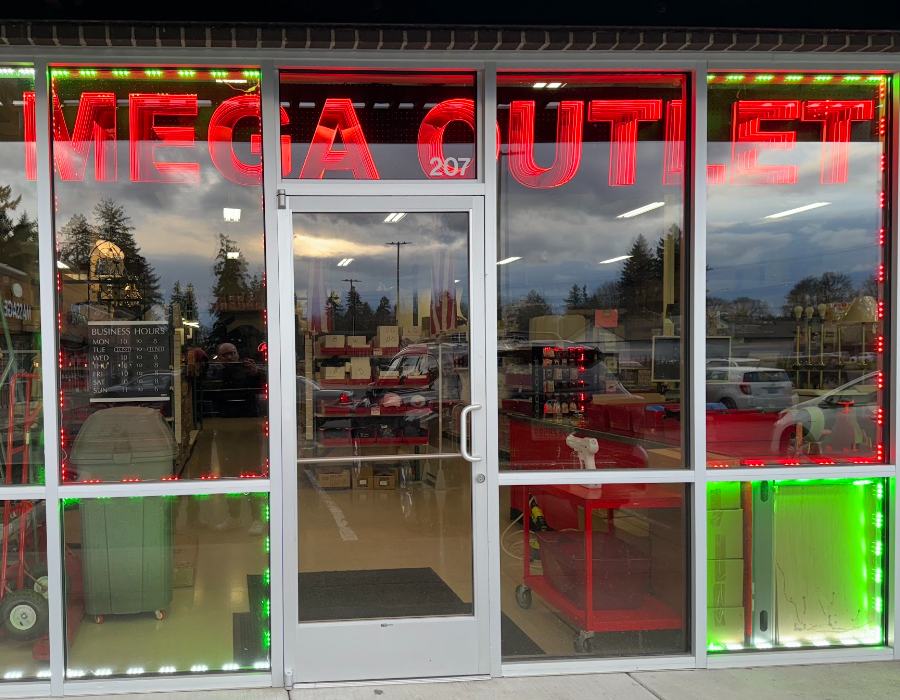 The lit MEGA OUTLET storefront entrance at Suite 207
